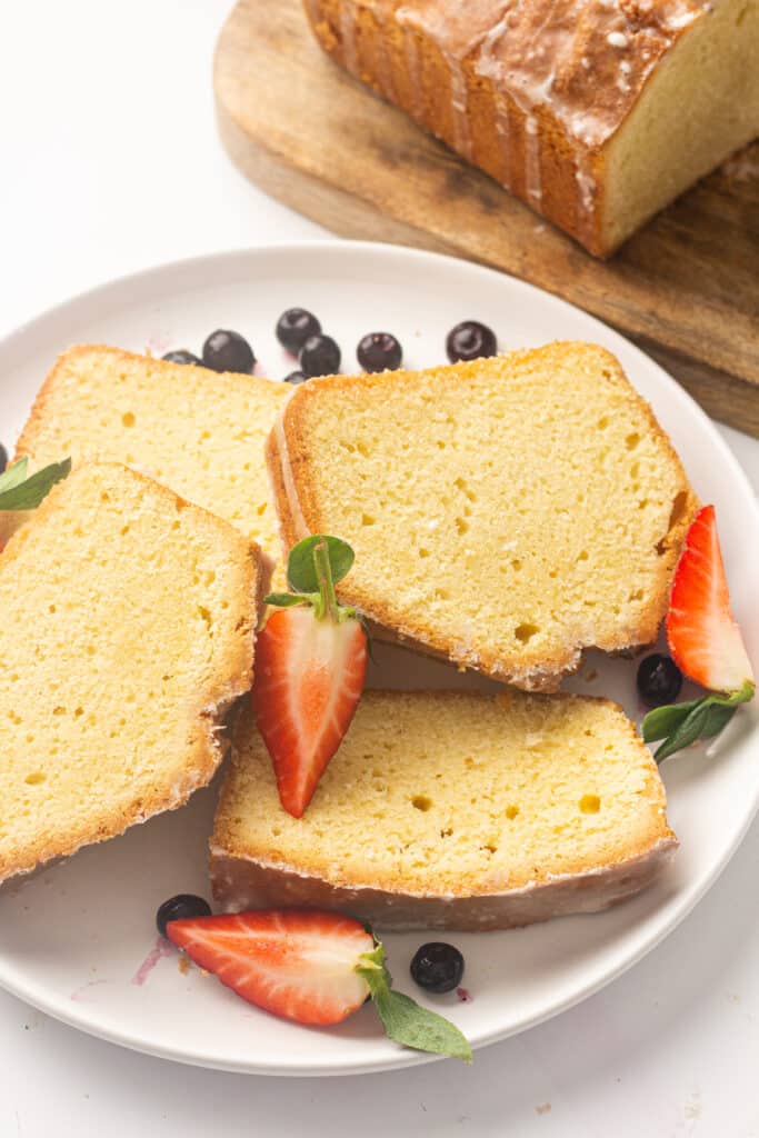 Slices of the air fryer pound cake on a white plate and fruit 