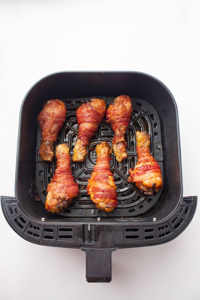 A picture of cooked bacon-wrapped chicken drumsticks 