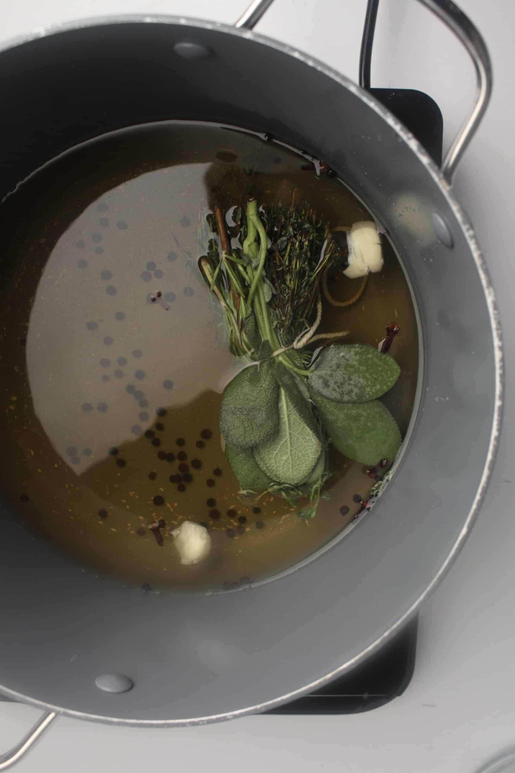 Process picture of the herbs, peppercorns and garlic in the water in the pot