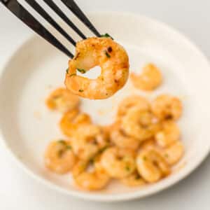 Air Fryer Garlic Butter Shrimp on a plate being held up with a fork